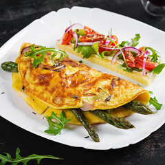 Keto breakfast. Omelette with cheese, red onion and asparagus on dark table. Italian frittata. Keto, ketogenic lunch.
