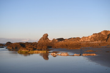 Beautiful rocks look like statue reflects on beach at Byron Bay, NSW, Australia during sunset.