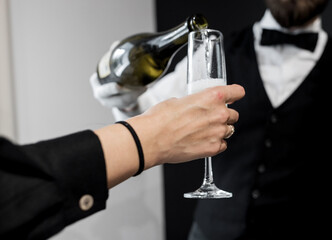  waiter pouring champagne into a flute.
