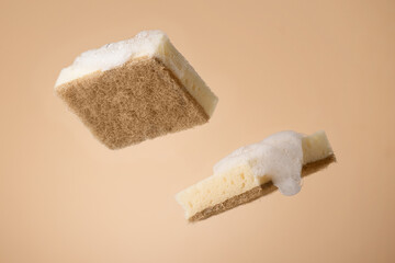 Natural dishwashing sponge with soap foam over beige background. Eco friendly housework objects.