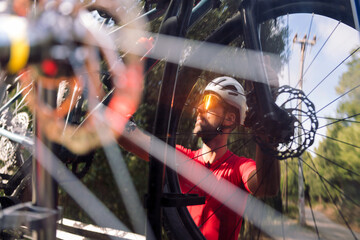 reflection in the rear window of a van of a young man wearing a helmet and cycling goggles taking...