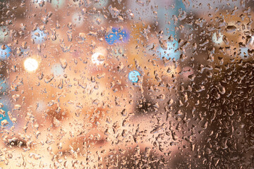 Frozen raindrops on the glass, raindrops on the window. In the background, a blurry plan, at home, in the windows, there is light with a bokeh effect.