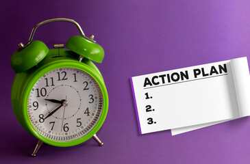 Action Plan numbered 1 2 3 writing on a notepad. notepad on purple background with a green table clock.