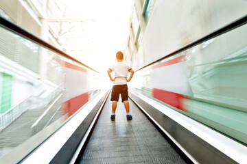 Rear view of litlle boy on moving escalator