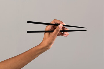 Black female hand with black chopsticks