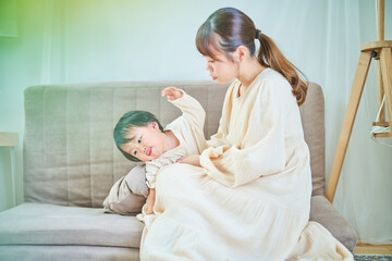 部屋で遊ぶ子どもと疲れた表情のお母さん