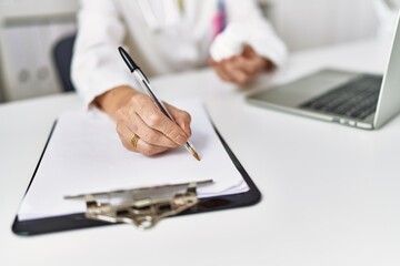 Middle age hispanic woman wearing doctor uniform holding pills at clinic