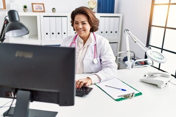 Obraz na płótnie Canvas Middle age hispanic woman wearing doctor uniform working at clinic