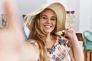 Young blonde girl wearing hat make selfie by the camera at clothing store