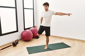 Young hispanic man stretching at sport center