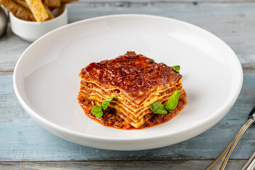 Bechamel sauce and minced meat lasagna on wooden table