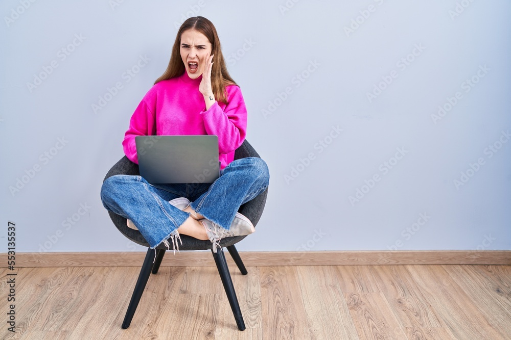 Poster young hispanic girl working using computer laptop shouting and screaming loud to side with hand on m