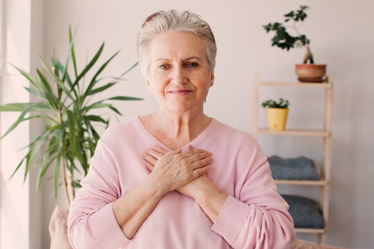 Happy Adult Female Volunteer Holding Folded Hands On Chest