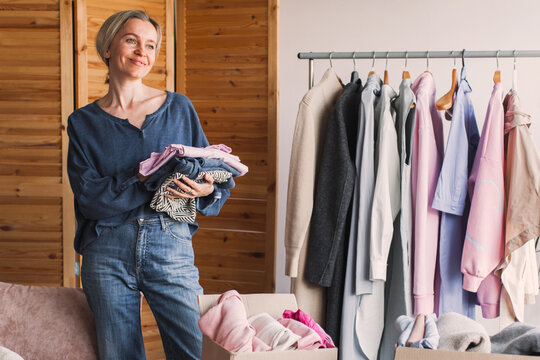 Happy Middle Aged Woman Holding Cardboard Recycling Box With Clothes