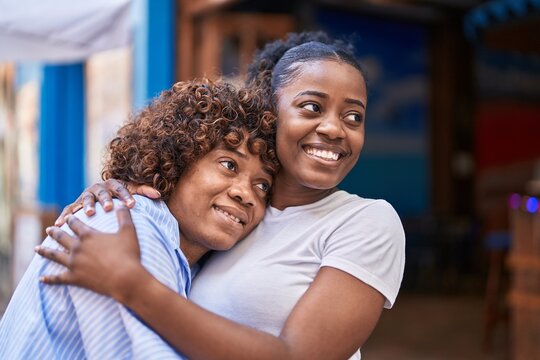 African american women mother and daughter hugging each other at street