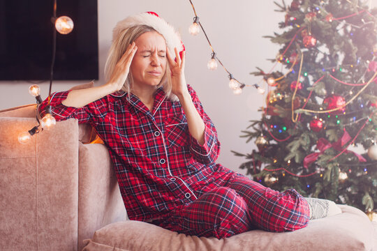 Sad woman have headache in front of Christmas tree