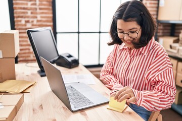 Young woman ecommerce business worker holding reminder paper at office