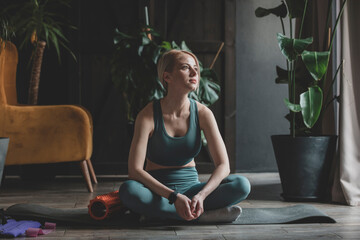 Woman day dreaming sitting on exercise mat in living room