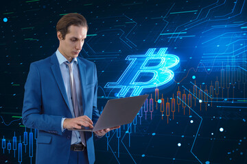 Attractive thoughtful young european businessman with laptop and glowing bitcoin hologram on blurry background. Cryptocurrency and finance concept.