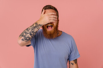 Ginger excited man with beard screaming while covering his eyes