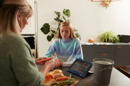 Girl with mother preparing food in kitchen at home