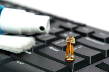 Miniature people toy figure photography. Sweeper workers cleaning mechanical keyboard using broom,...