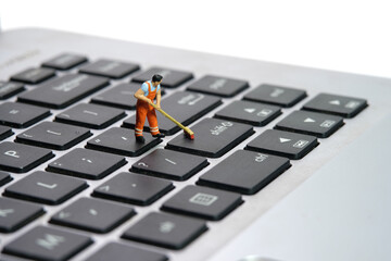 Miniature people toy figure photography. Sweeper workers cleaning notebook laptop keyboard using...