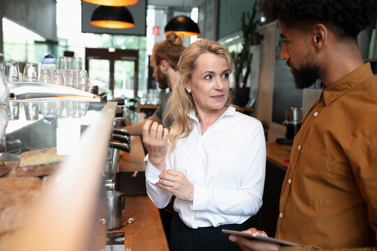 Cafe owner talking to barista in coffee shop