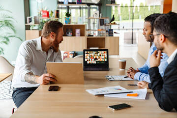 Group of multiethnic businesspeople talking with team during video conference in office