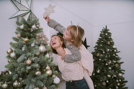 Daughter putting star on Christmas tree with mother at home