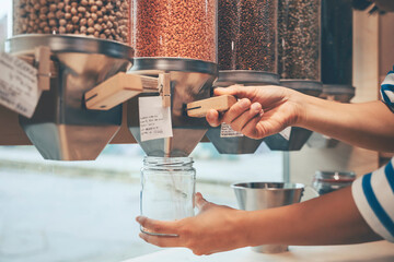 Hands of woman holding mason jar under food dispenser in store