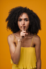 Young beautiful frowning curly woman doing silence gesture