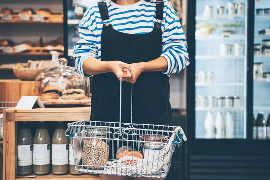 Customer holding groceries in shopping basket at retail shop
