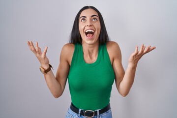 Young woman standing over isolated background celebrating mad and crazy for success with arms...