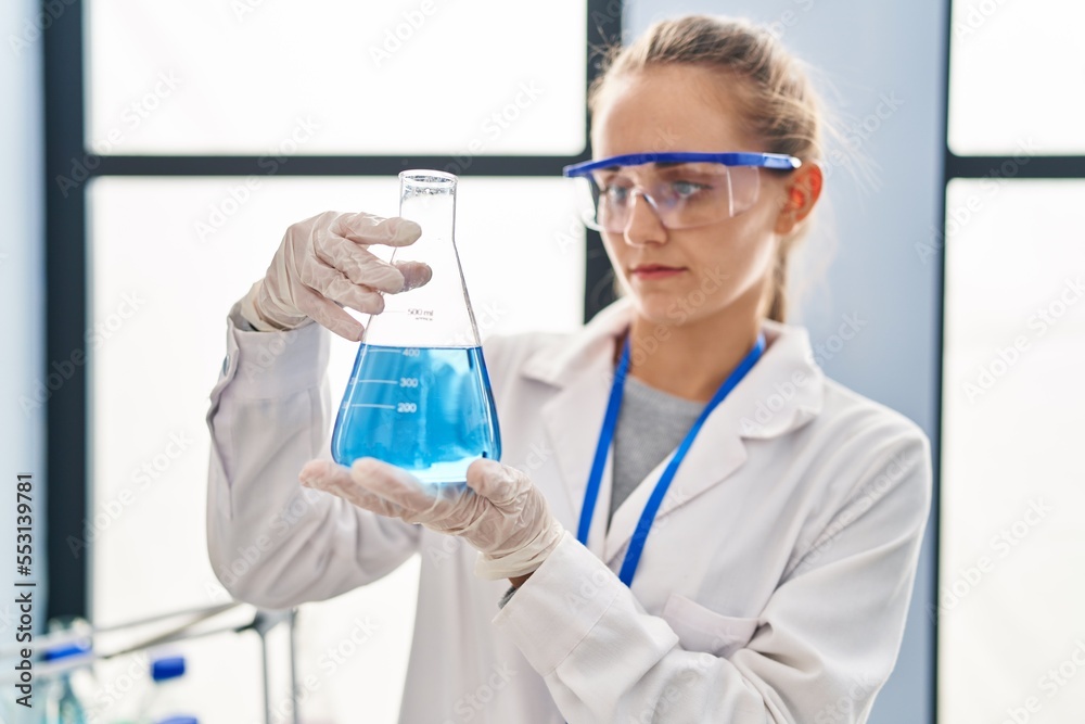 Poster young blonde woman wearing scientist uniform holding test tube at laboratory