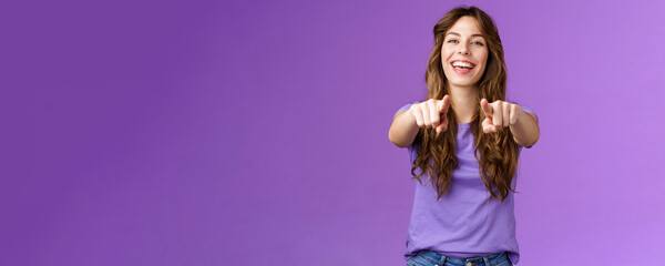 Its you. Friendly glad joyful happy curly-haired girl pointing fingers camera smiling broadly laughing congratulate friend singing song indicating boyfriend make choice stand purple background