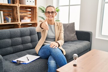 Fototapeta premium Young woman working at consultation office smiling friendly offering handshake as greeting and welcoming. successful business.