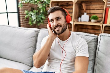 Young hispanic man smiling confident listening to music at home