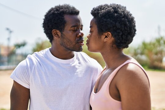 African american man and woman couple standing together kissing at park