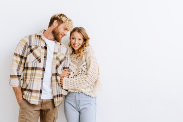 Young couple standing over white wall and hugging