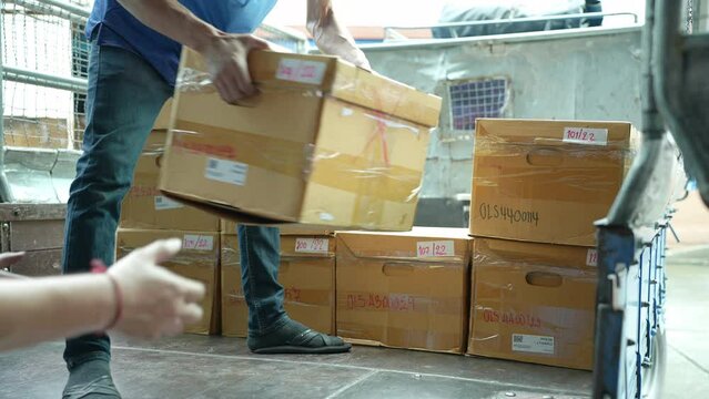 Man unloading cardboard boxes for storing documents from the trunk of trucks for recycling.
