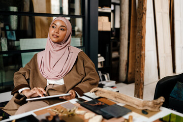 Female muslim designer working on tablet at workshop