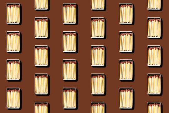 Pattern of rows of matchboxes flat laid against brown background