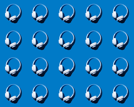 Pattern of rows of headphones flat laid against blue background
