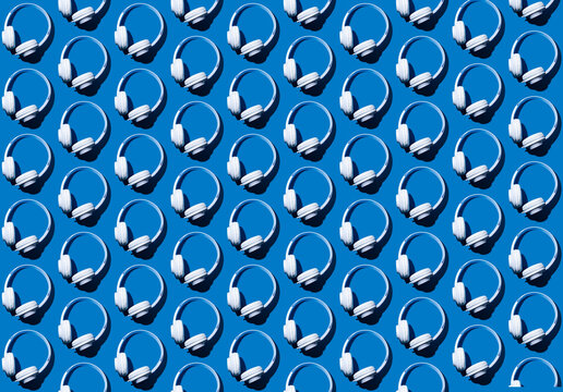 Pattern of rows of headphones flat laid against blue background