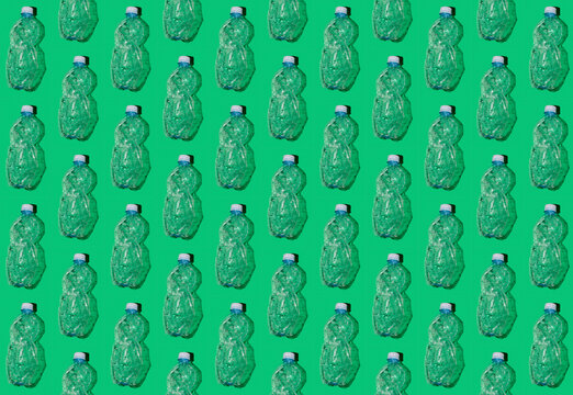 Pattern of rows of empty plastic bottles flat laid against green background