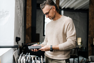 Middle-aged male designer working with samples in workshop