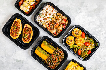 Studio shot of variety of take out food including chop suey, stuffed potatoes, fajitas, rice muffins, ricotta rolls, various salads and terrine