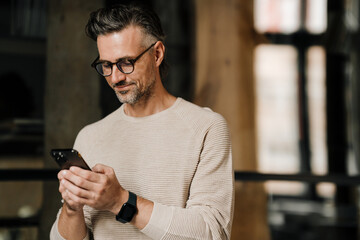 Middle-aged man using smartphone indoors
