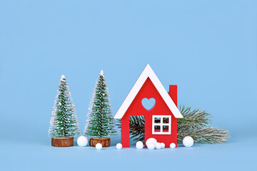 Naklejka premium Winter decoration with small red house, Christmas trees, snowballs and fir cones on blue background